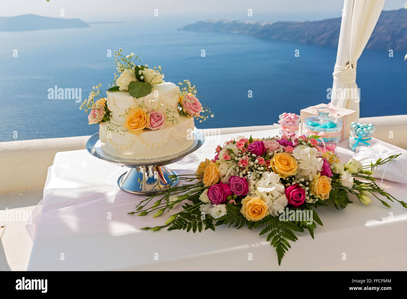 Wedding cake and bouquets of flowers on the table, against the sea. Greece. Stock Photo