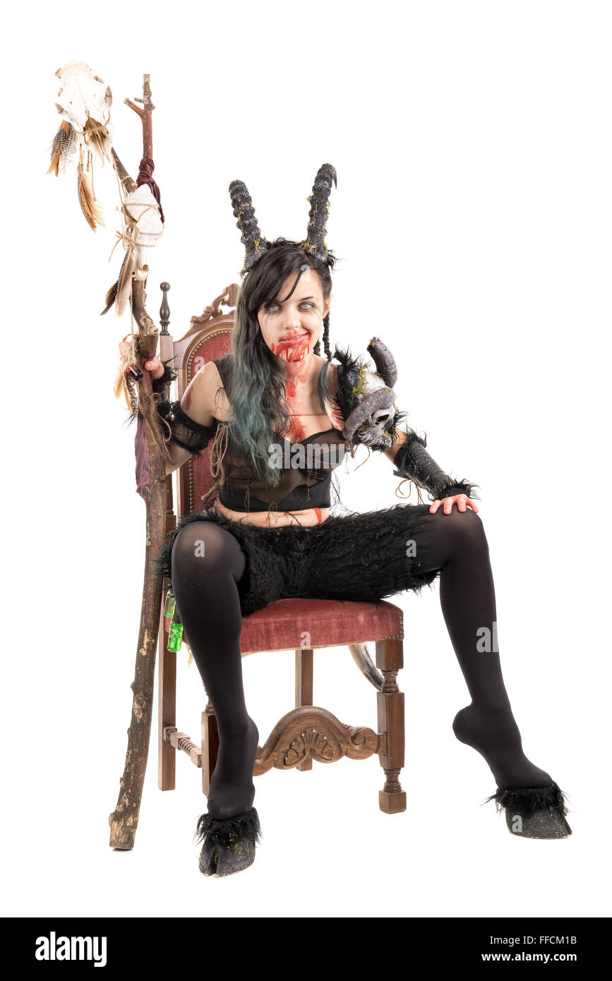 Faun sorceress with big horns and blood in a chair isolated in white Stock Photo