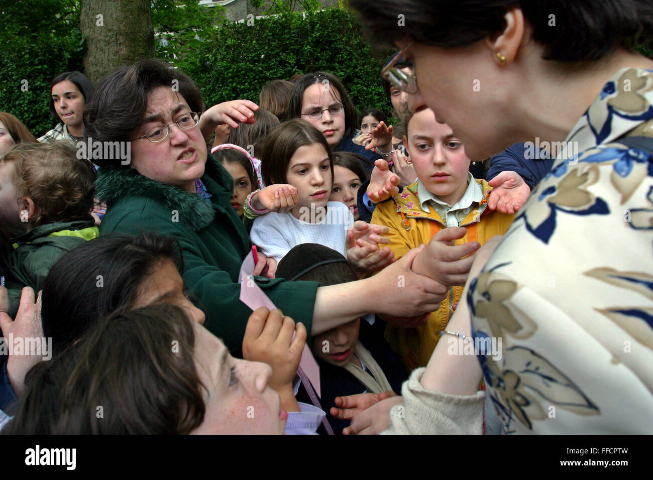 Women and children struggle to get vouchers for free kosher ice cream, the only kosher ice cream van in the UK visiting a community event in Allen Gardens, Stamford Hill to celebrate Lag B’Omer. Lag B’Omer is the holiday celebrating the thirty-third day of the (counting of the) Omer. Jews celebrate it as the day when the plague that killed 24,000 people ended in the holy land (according to the Babylonian Talmud). Other sources say the plague was actually the Roman occupation and the 24,000 people died in the second Jewish – Roman war  (Bar Kokhba revolt of the first century).  Bonfires (used a Stock Photo