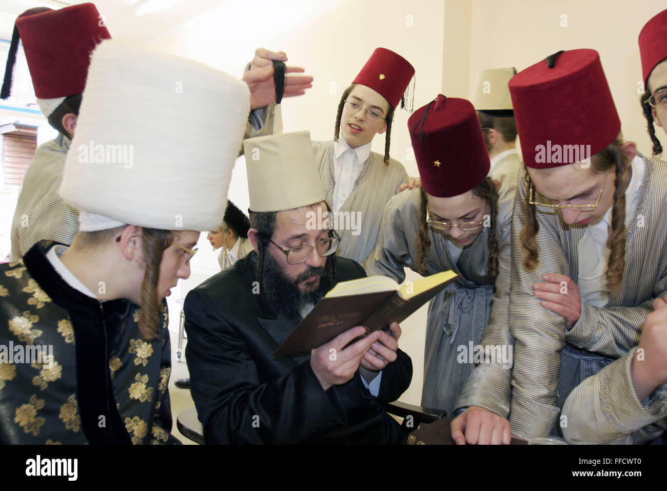 During the Jewish festival of Purim a group of Orthodox Jewish boys from the Viznitz Yeshiva (school) in fancy dress visit local businessmen to collect money for their school. Some of the businessman that they visit read a prayer to the group. The young boys drink alcohol at every house they visit during the day. Stock Photo