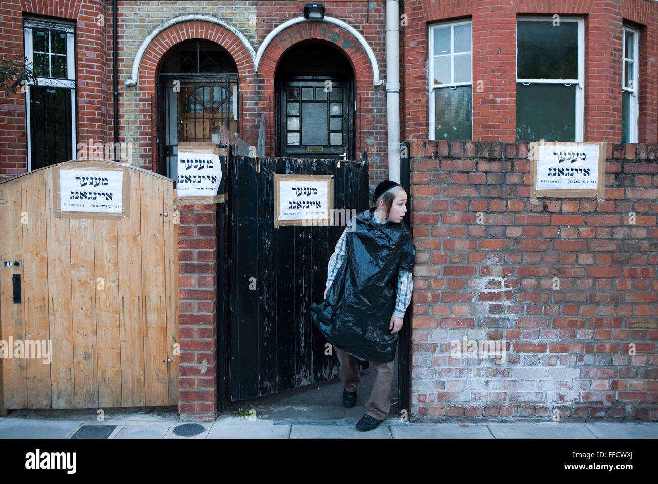 A young Jewish boy keeps watch on the school gate during Kapparot in Stamford Hill, London. Kapparot is a custom in which the sins of a person are symbolically transferred to a fowl, a rooster for a male and a hen for female. One or two local schools use their playgrounds for this practice, it takes place at dawn. Stock Photo