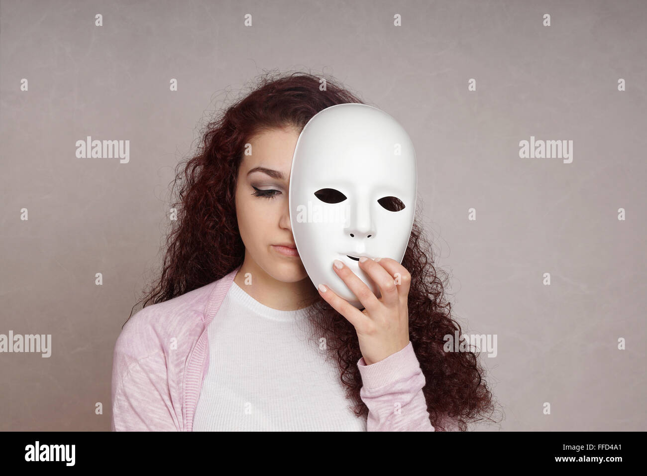 sad girl hiding face behind mask Stock Photo Alamy