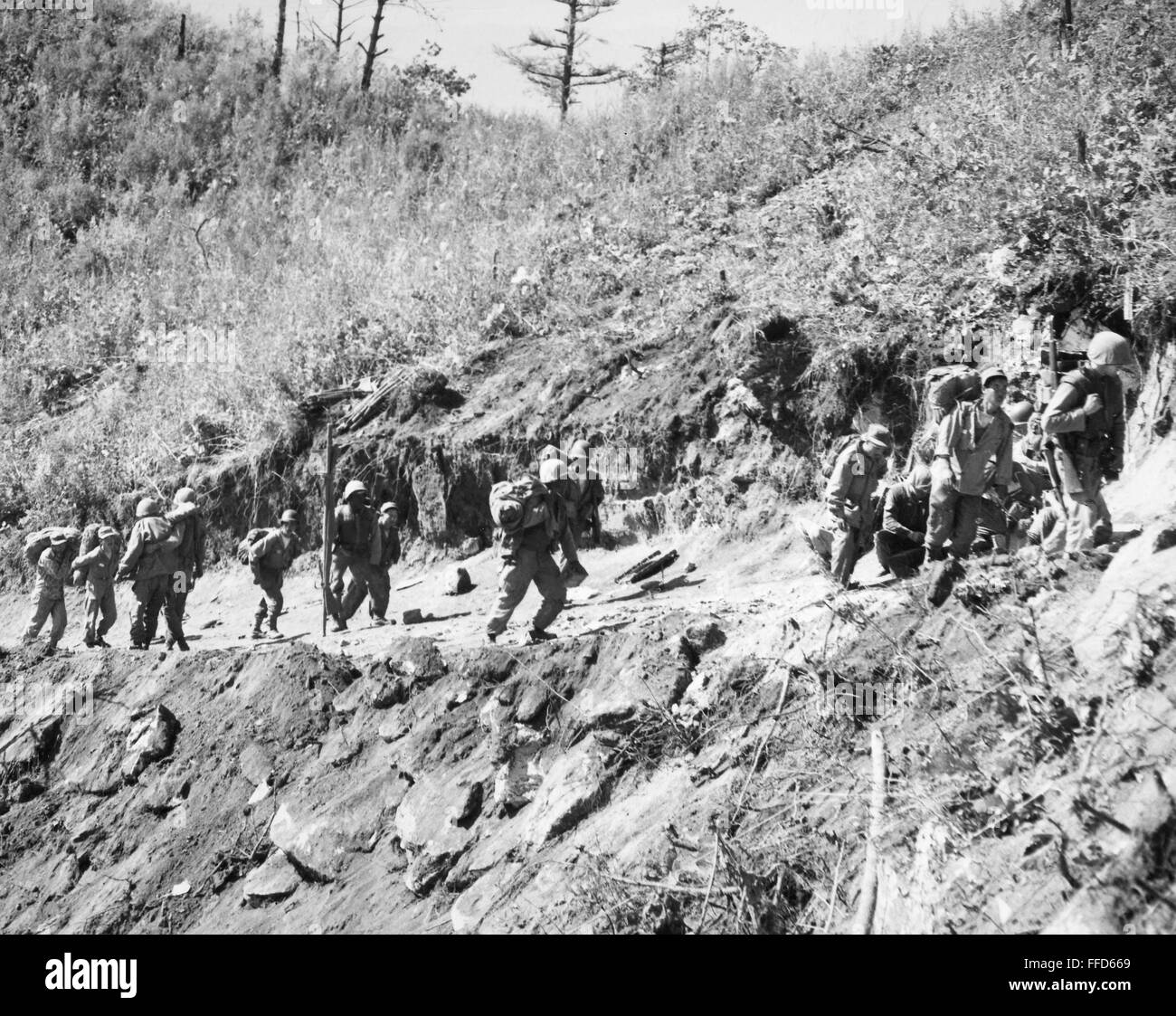 KOREAN WAR: TRIANGLE HILL. /nSoldiers of the U.S. 7th Division and South Korean serivce corps men carrying supplies up the southern slope of Triangle Hill, as a wounded soldier, left, is helped down the trail, and another wounded soldier is assisted on th Stock Photo