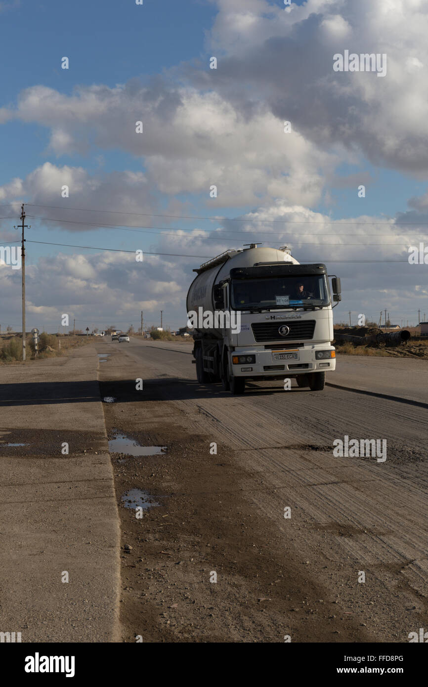 A truck passes by on the road between Khyva and Bukhara across the Kyzylkum desert, or Red Desert Stock Photo