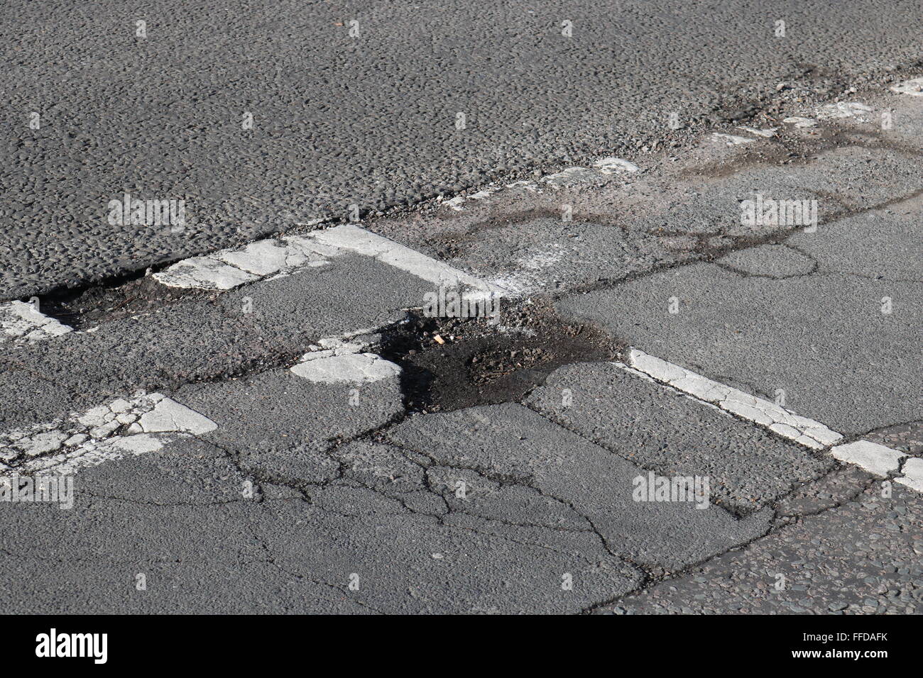 A pothole at the junction of a main road and residential road in Knaphill, Woking, Surrey. Stock Photo