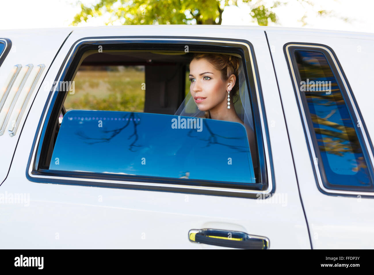Bride looks out of the window a white limousine Stock Photo