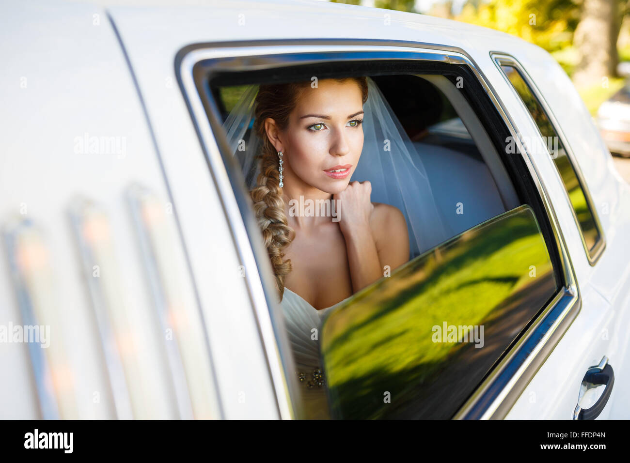 Bride looks out of the window a white limousine Stock Photo