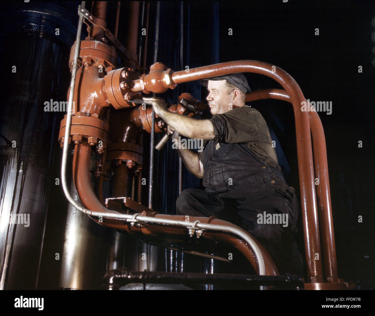 STEEL HYDRAULIC PRESS, 1942. /nMaintenance man working on a cold steel