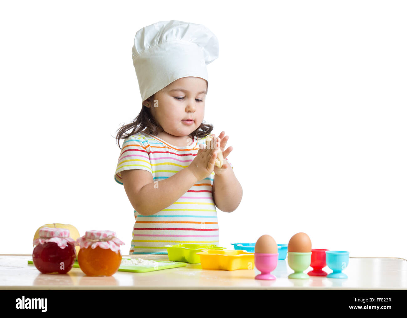 Child little girl kneading the dough for the cookies, isolated on white Stock Photo