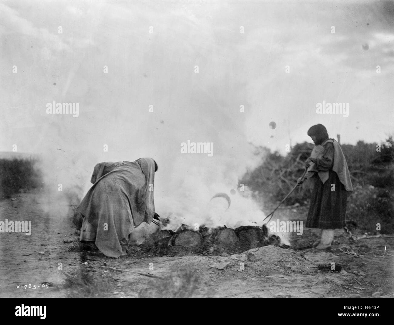 PUEBLO POTTERS, c1905. /nPotters firing ceramics in a kiln at the Santa Clara Pueblo in New Mexico. Photograph by Edward Curtis, c1905. Stock Photo