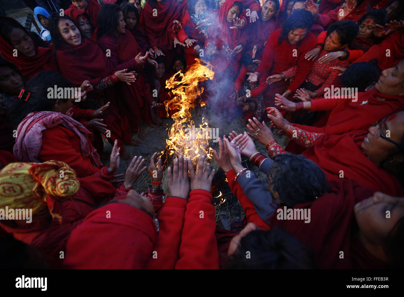 Kavre, Nepal. 12th Feb, 2016. Nepalese devotee women keep themselves warm next to a bonfire after taking a holy bath during the month-long Swasthani Bratakatha festival, devoted to goddess Shree Swasthani in Panauti, Kavre, Nepal. Men devotees recite Holy Scripture and women pray for the well being of their spouses throughout the month-long fast via travelling barefooted to holy shrines for worship. © Skanda Gautam/ZUMA Wire/Alamy Live News Stock Photo
