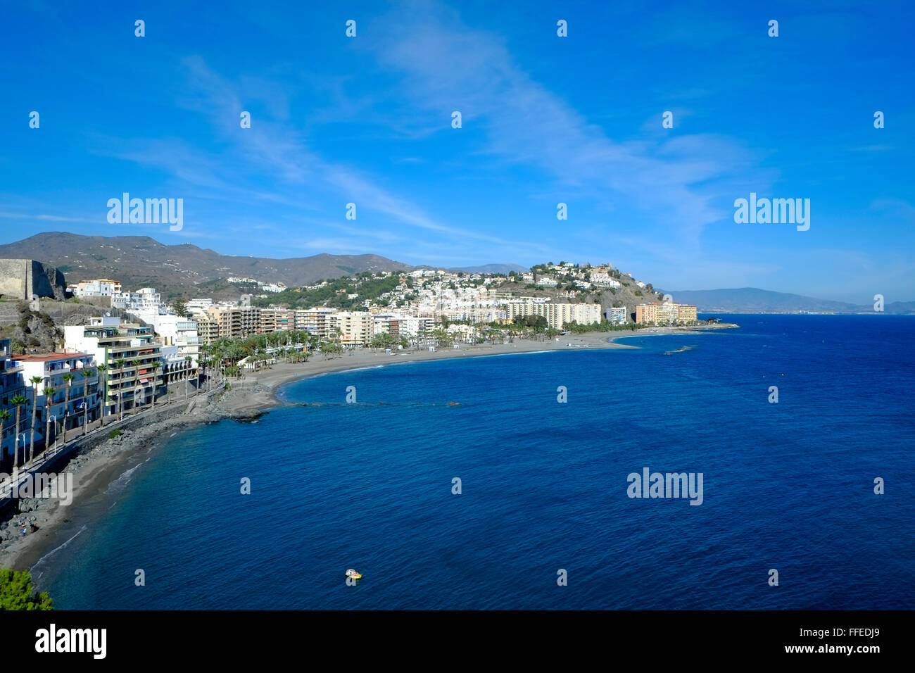 The beachfront with low rise buildings and cerulean blue Mediterranean sea on a sunny late autumn day at Almuñécar, Costa Tropical, Andalucia. Spain Stock Photo