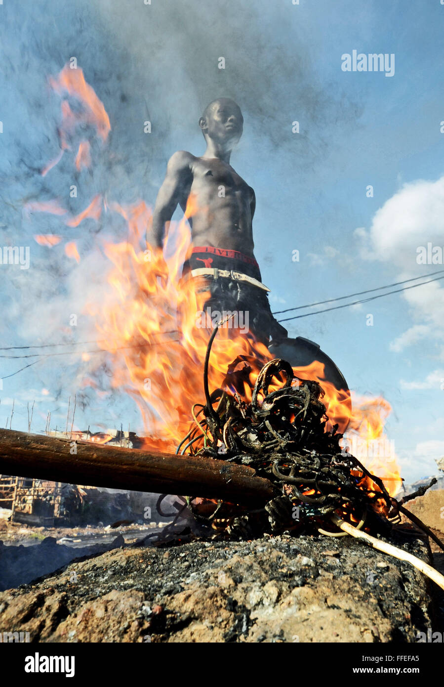 A youth burns old old cables to recycle the copper wire inside in