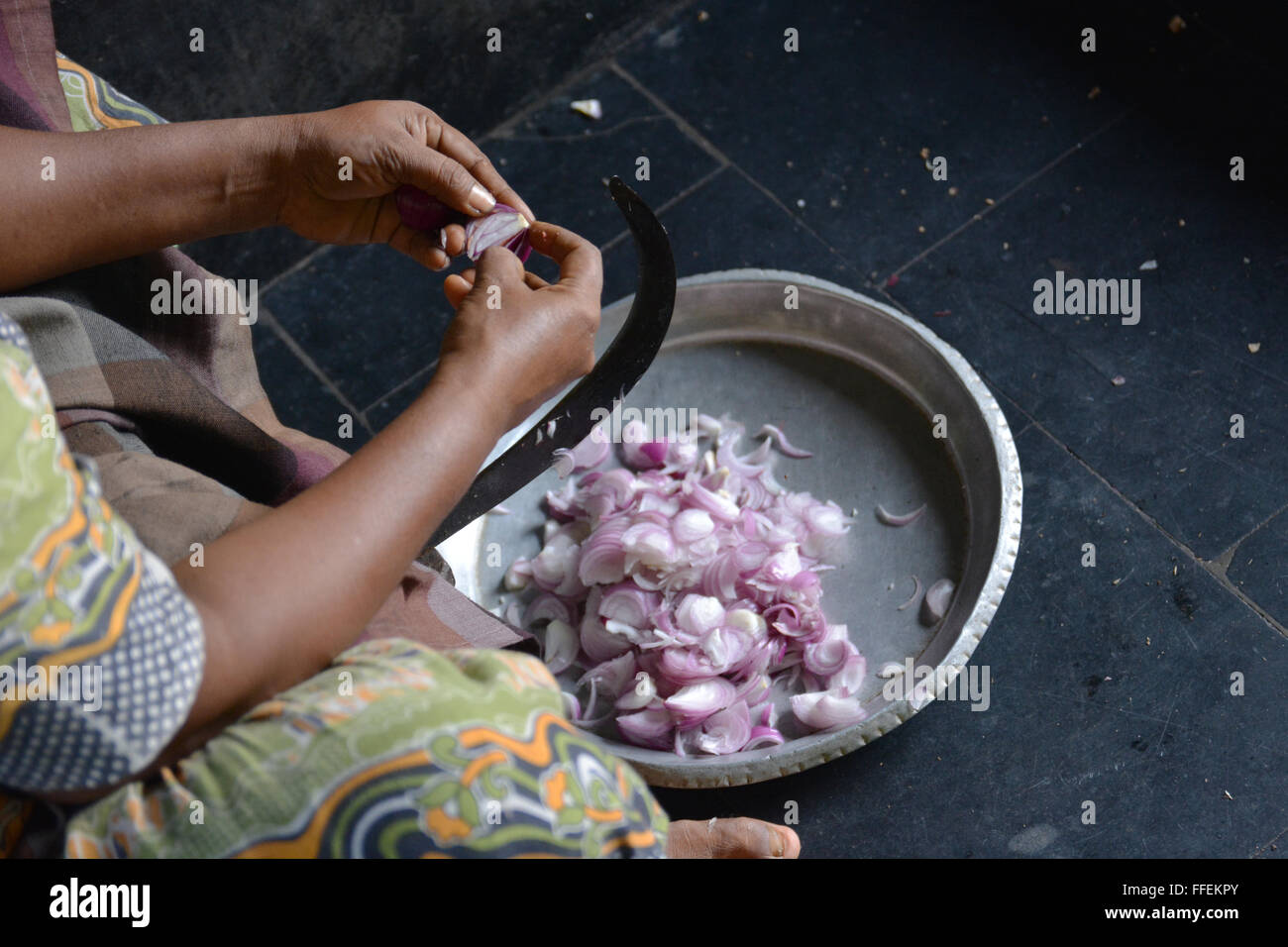 Mumbai, India - October 28, 2015 - Woman cutting chili and onions on a traditional cutting stool  in indian kitchen Stock Photo