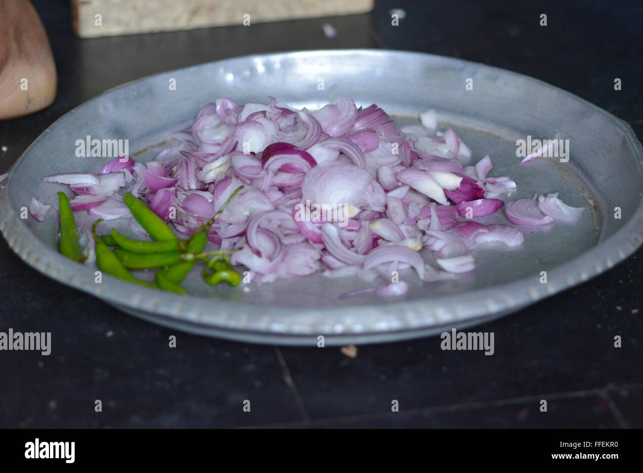 Mumbai, India - October 28, 2015 - Woman cutting chili and onions on a traditional cutting stool  in indian kitchen Stock Photo