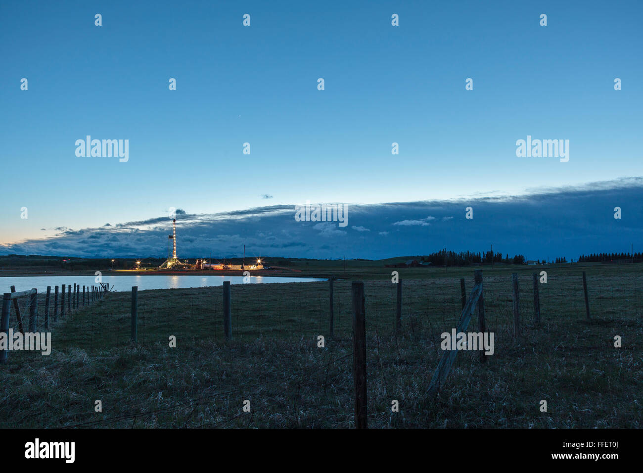 A drilling rig operates in the prairie grasslands of Southern Alberta next to Jumping Pound Creek near Calgary in a resource based energy economy Stock Photo