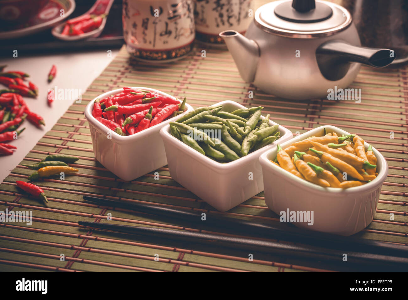 Red, green and yellow peppers on an oriental style table. Depth of field with focus on center of the image. Stock Photo