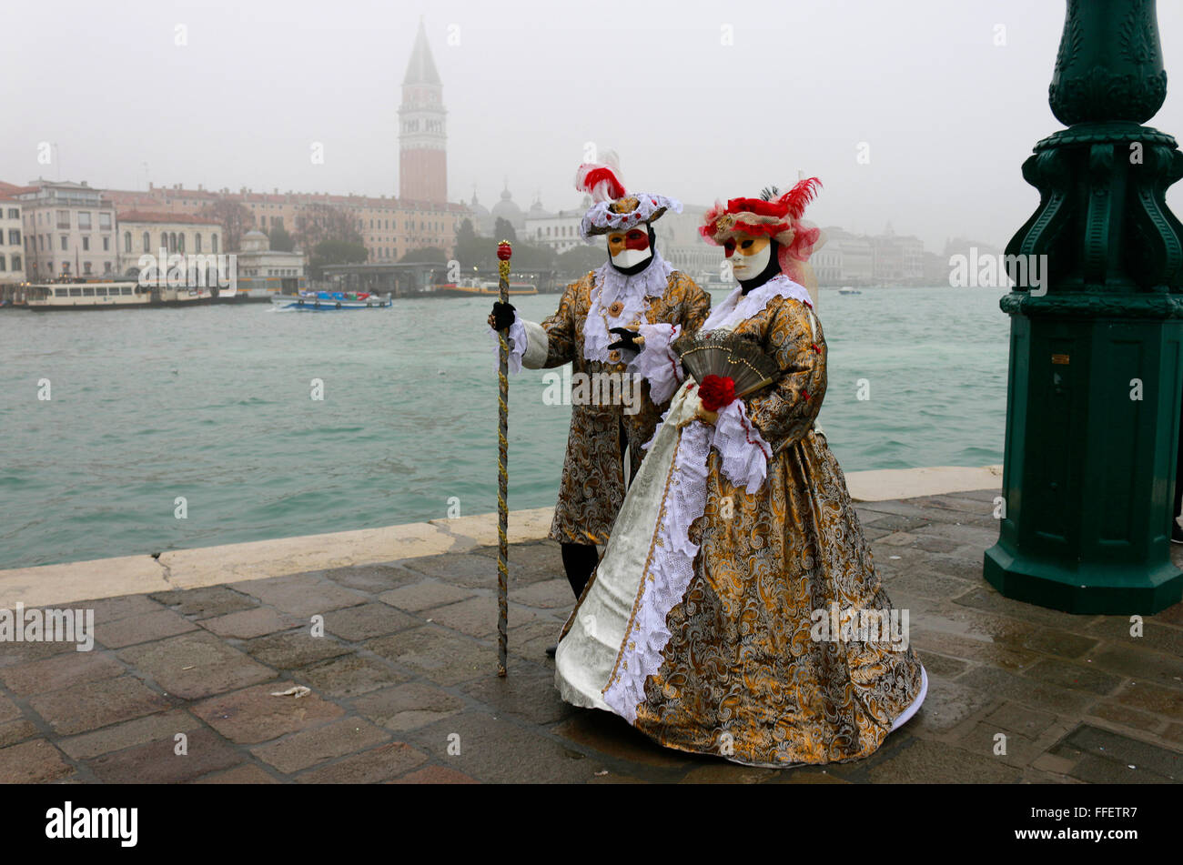 Maskierte Personen zum Karneval, im Hintergrund der Markusplatz mit Markusturm, Venedig, Italien. Stock Photo