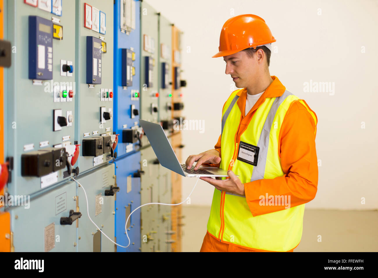 experienced electrician working on laptop in substation Stock Photo