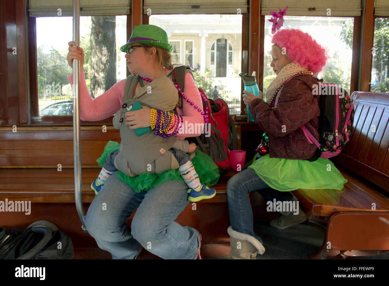 A mother rides the streetcar home with her daughter and baby after parades on Mardi Gras day, New Orleans, LA. Stock Photo