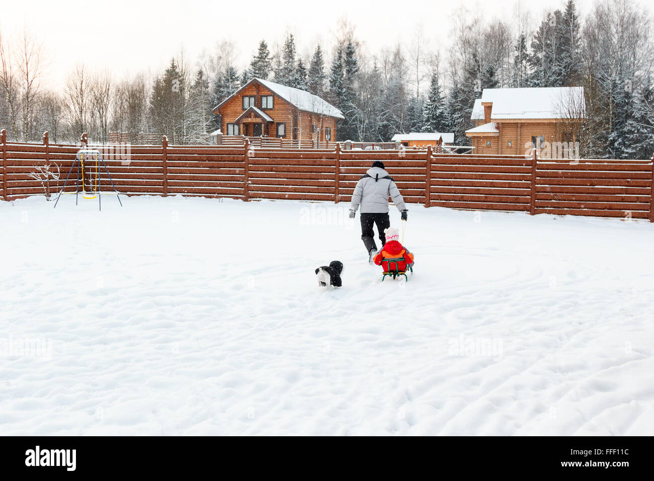 Dad daughter and dog sledding in the backyard Stock Photo