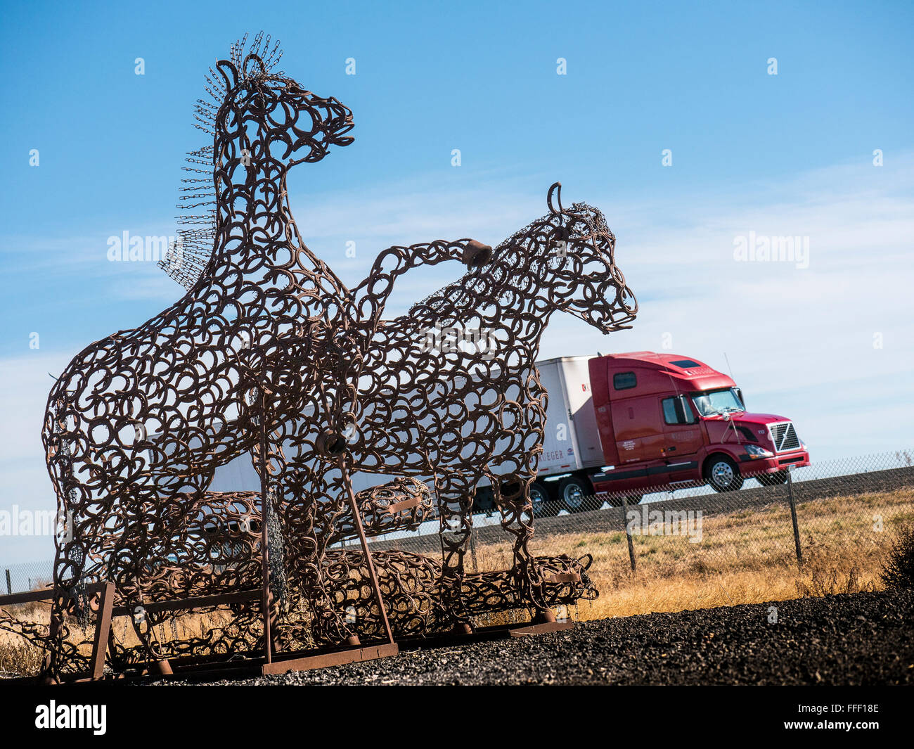 The sun shines through a wild horse sculpture made of horseshoes near