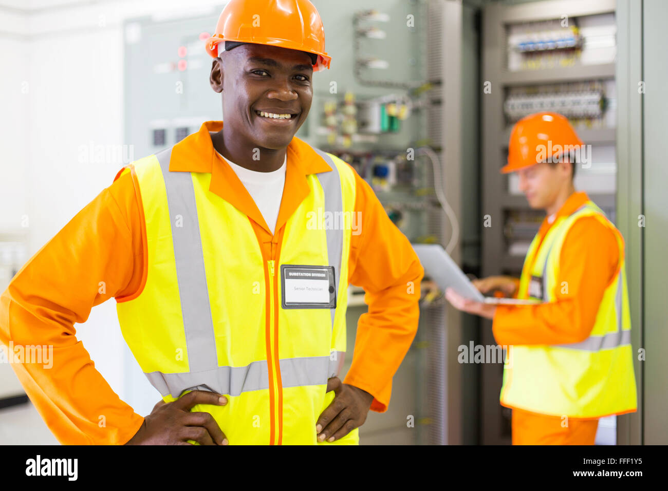 portrait of happy African industrial technician in front of colleague Stock Photo