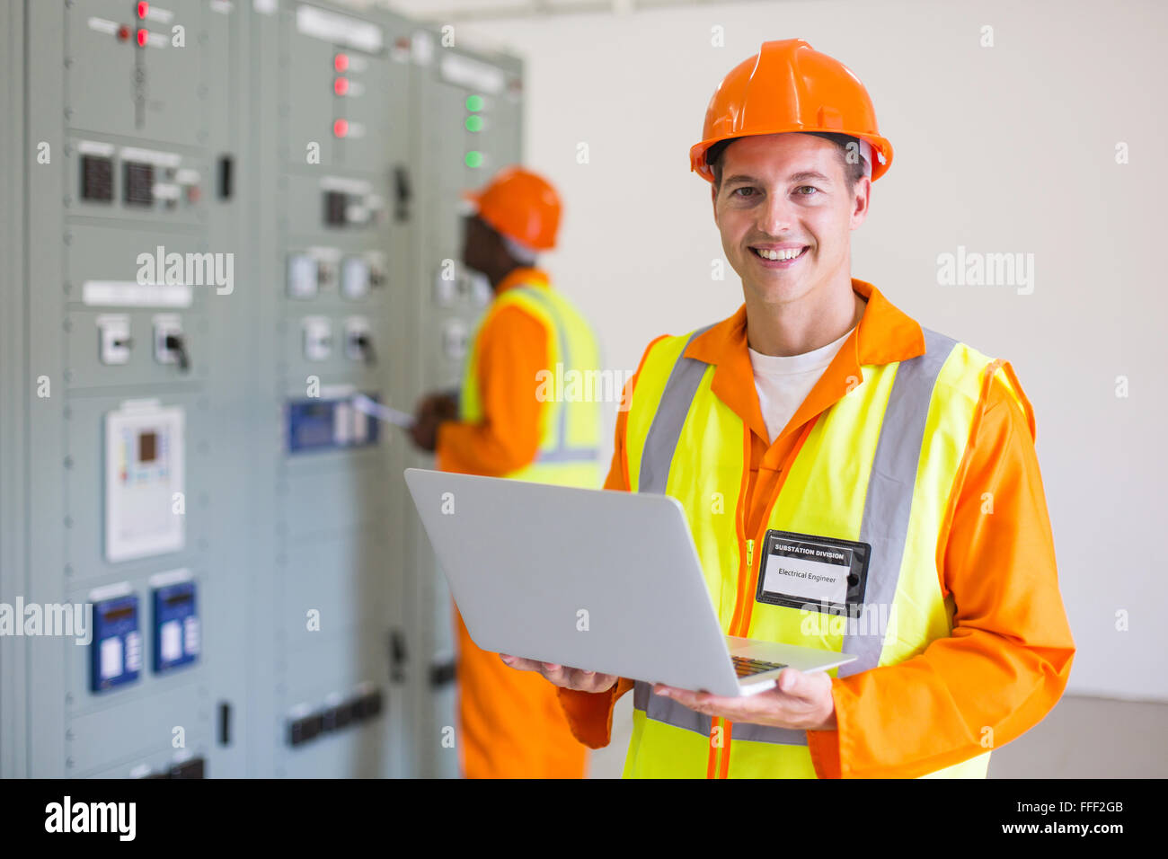 portrait of modern young electrician with laptop computer Stock Photo