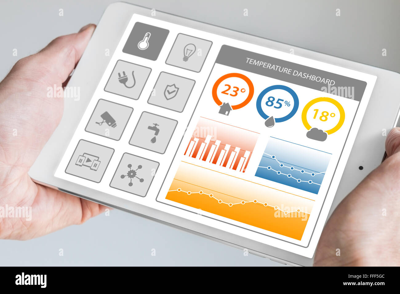 Smart home dashboard in order to control home appliances. Hand holding modern tablet with dashboard displaying charts. Stock Photo