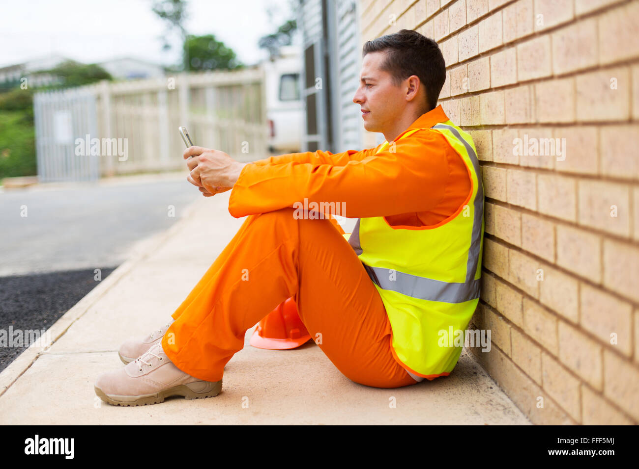 relaxed electrician using smart phone during break Stock Photo
