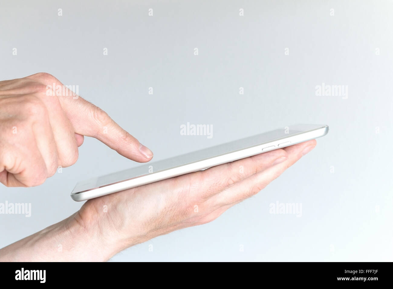 Male hand holding modern tablet or large smart phone. Other hand pointing at screen of mobile device with one finger. Concept of Stock Photo