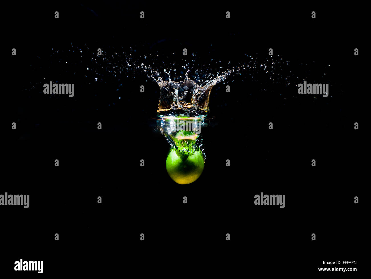 Green damson dropped into water with splash isolated on black background Stock Photo