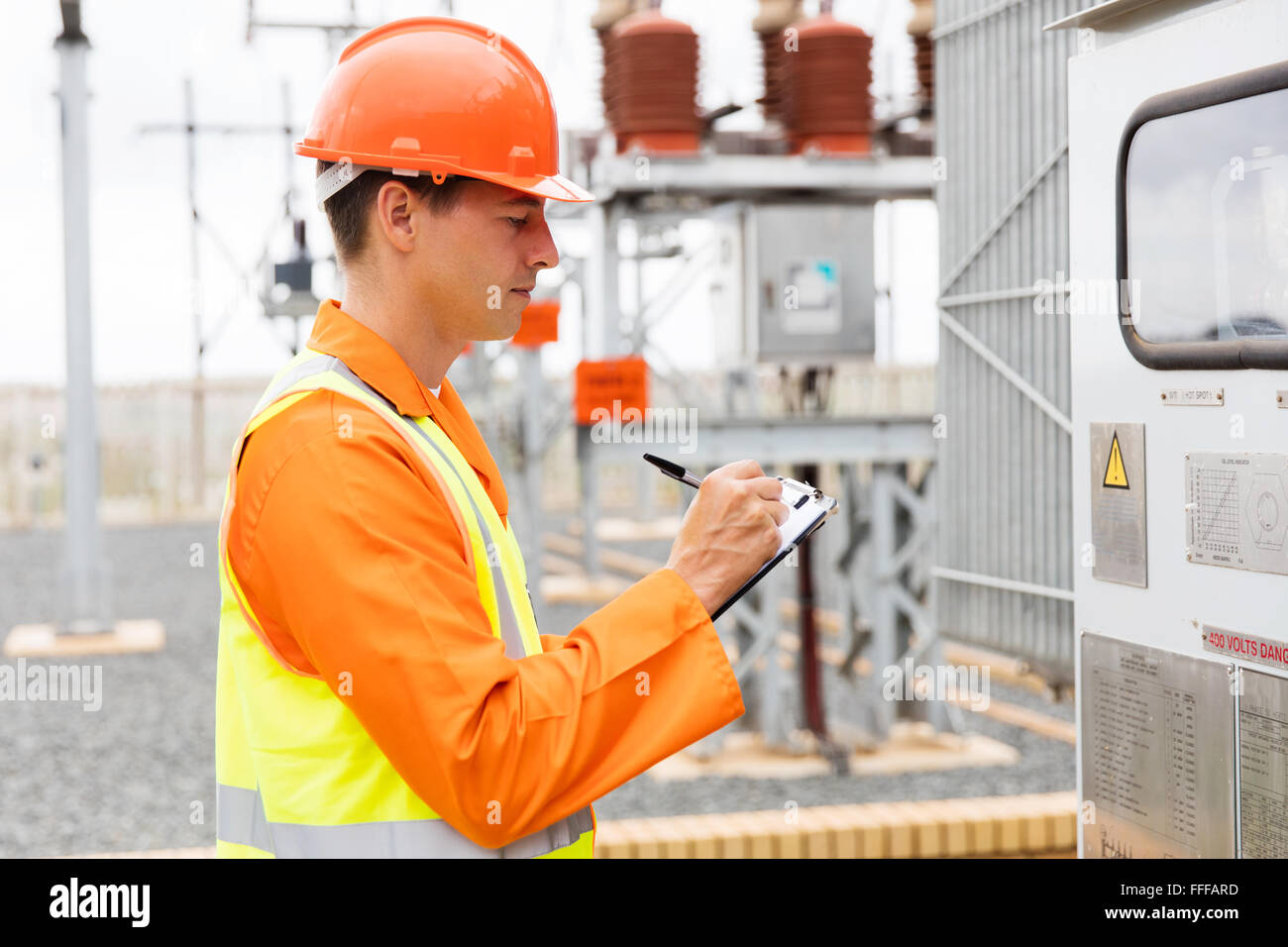 young electrician taking machine readings in substation Stock Photo