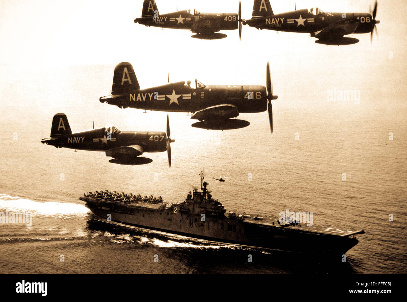F4U's (Corsairs) returning from a combat mission over North Korea circle the USS Boxer as they wait for planes in the next strike to be launched from her flight deck - a helicopter hovers above the ship.  September 4, 1951. (Navy) Stock Photo