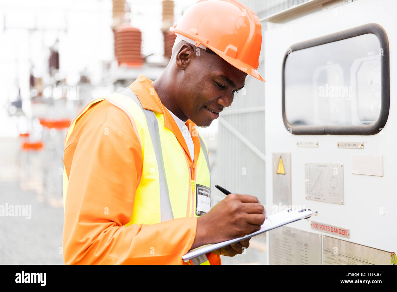 handsome African industrial technician taking machine readings Stock Photo