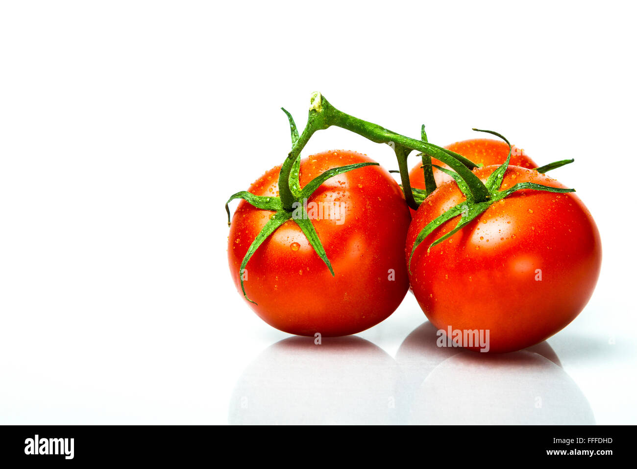 three ripe fresh tomato's on the vine with dew on them Stock Photo