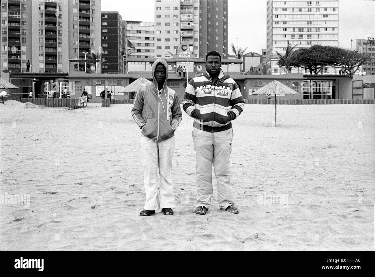Jan 4, 2016 - South Beach, KwaZulu-Natal, South Africa - Two men stand in front of the South Beach Life Saving Club. South Beach is a part of the City of Durban's longest uninterrupted stretch of beach sand. The City of Durban is on the eastern seaboard of South Africa and the people here are washed with the warm waters of the Indian Ocean. To the north of this stretch of sand are beaches with cafe society hang outs. To the south there is a pier with the upmarket Moyo's Restaurant at it's end and the uShaka Marine World complex and the private surf and sea clubs of the Vetches Beach area. Betw Stock Photo