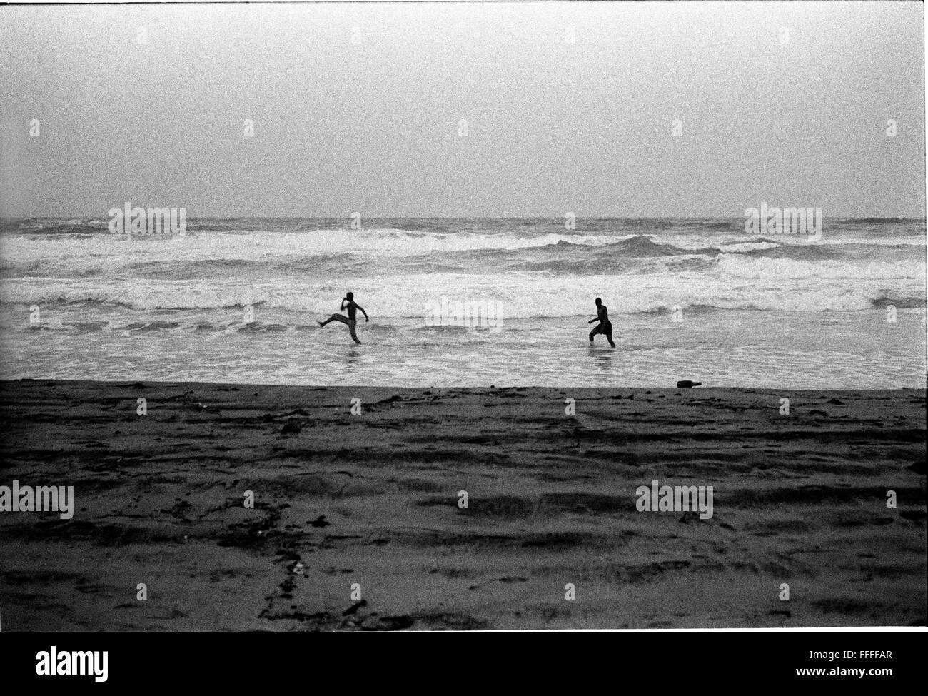 Jan 4, 2016 - South Beach, KwaZulu-Natal, South Africa - Two men running in the waves. South Beach is a part of the City of Durban's longest uninterrupted stretch of beach sand. The City of Durban is on the eastern seaboard of South Africa and the people here are washed with the warm waters of the Indian Ocean. To the north of this stretch of sand are beaches with cafe society hang outs. To the south there is a pier with the upmarket Moyo's Restaurant at it's end and the uShaka Marine World complex and the private surf and sea clubs of the Vetches Beach area. Between these northern and souther Stock Photo
