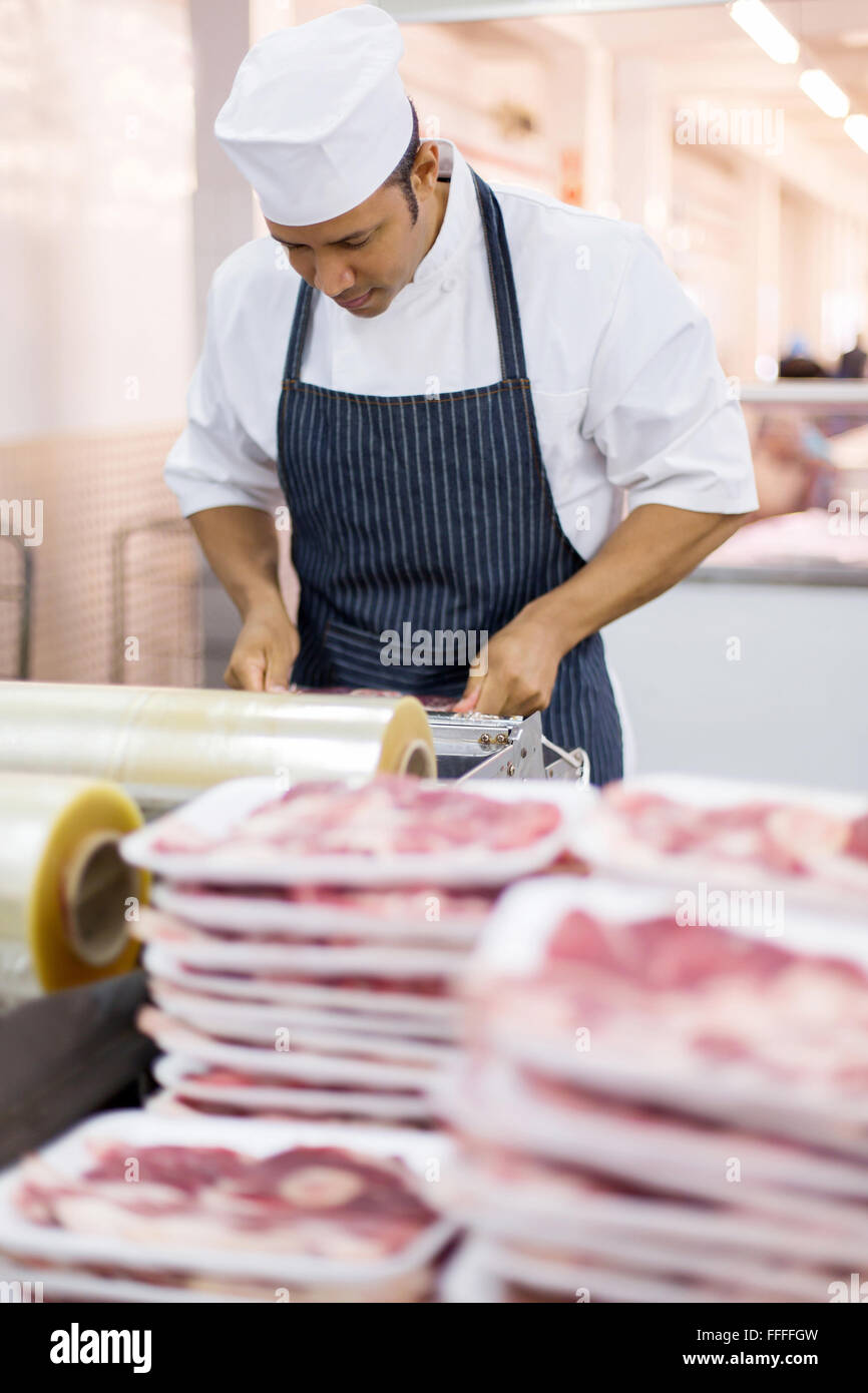 mid age butcher wrapping meat in butchery Stock Photo Alamy