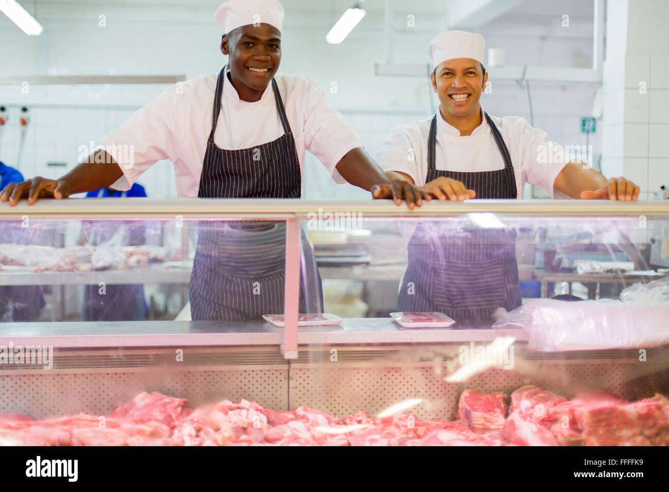 cheerful two butchers standing in butchery Stock Photo