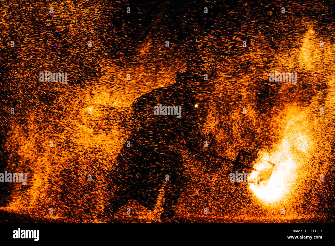 Fire show at night. Black silhouette of man against backdrop of fiery sparks Stock Photo