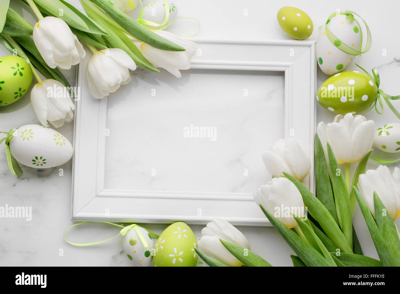Tulip,easter eggs and blank picture frame on white marble background Stock Photo