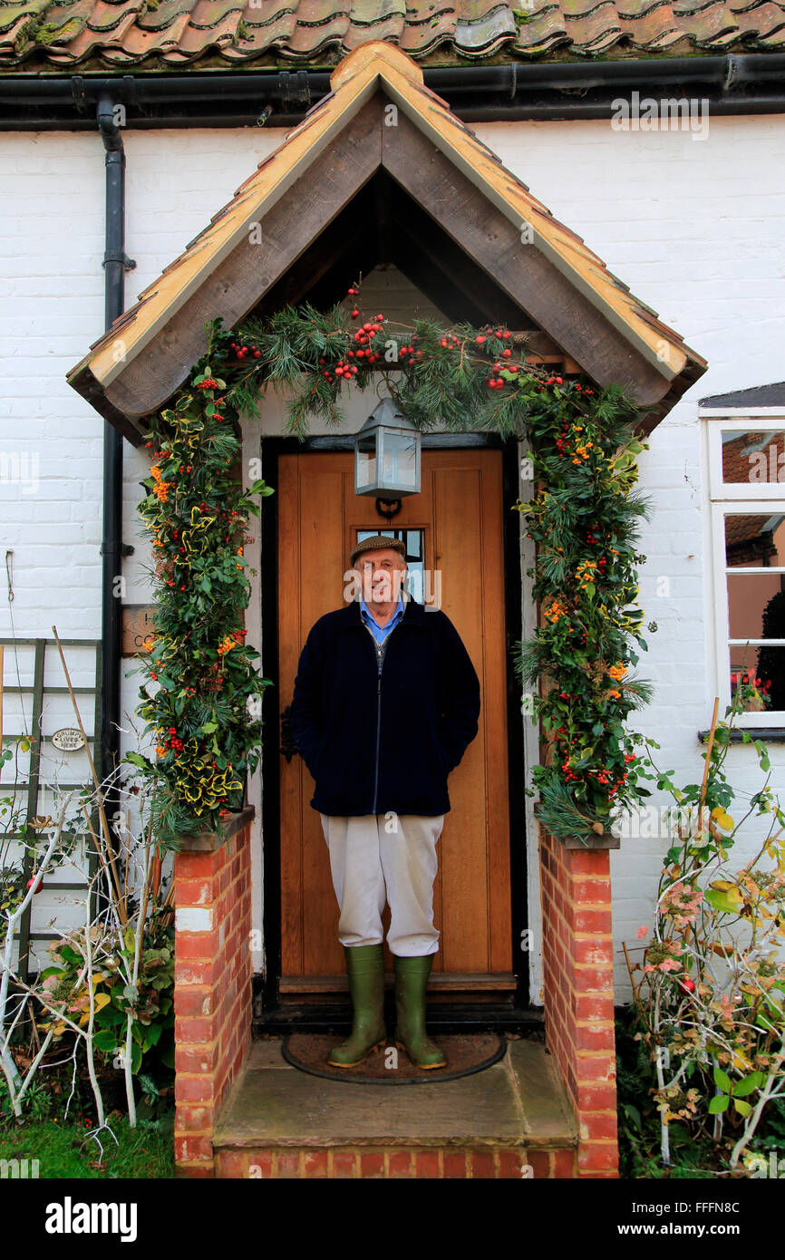 Elderly Man Standing In His Decorated Porch Having It For Christmas