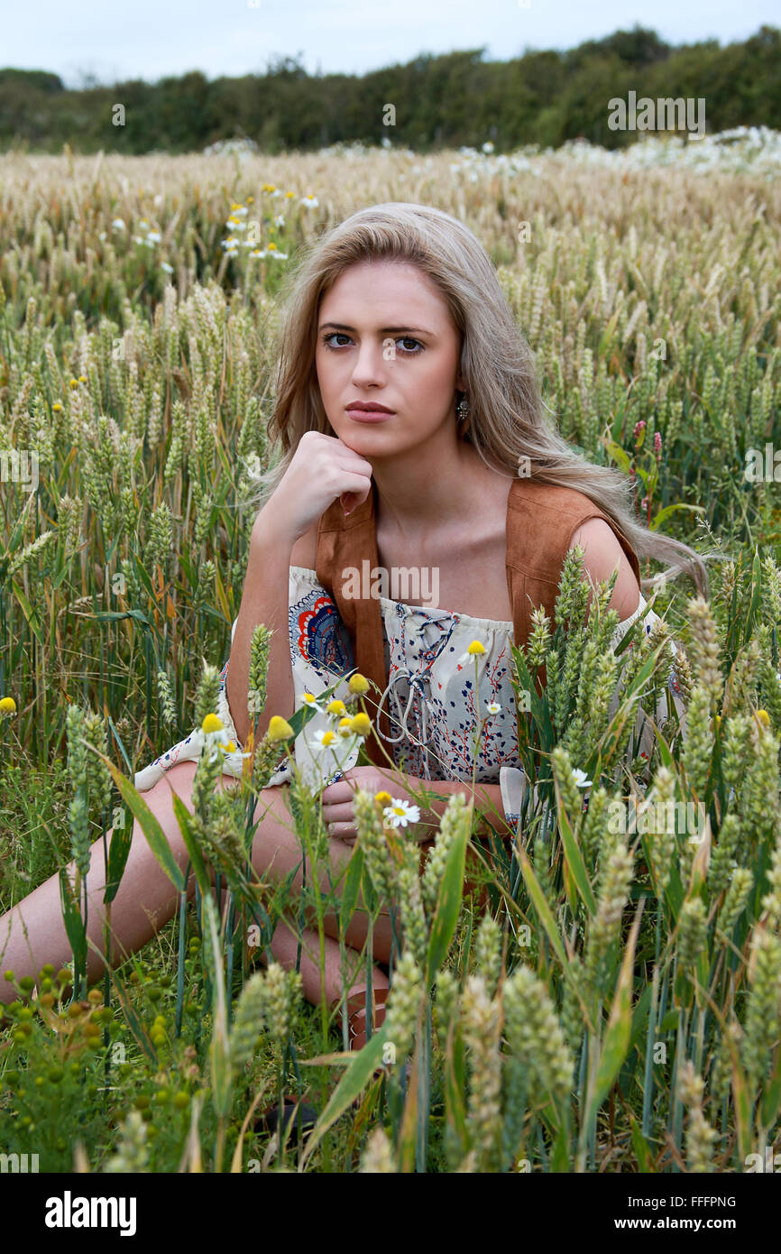 Beautiful girl sitting in a wheat field looking towards camera Stock ...