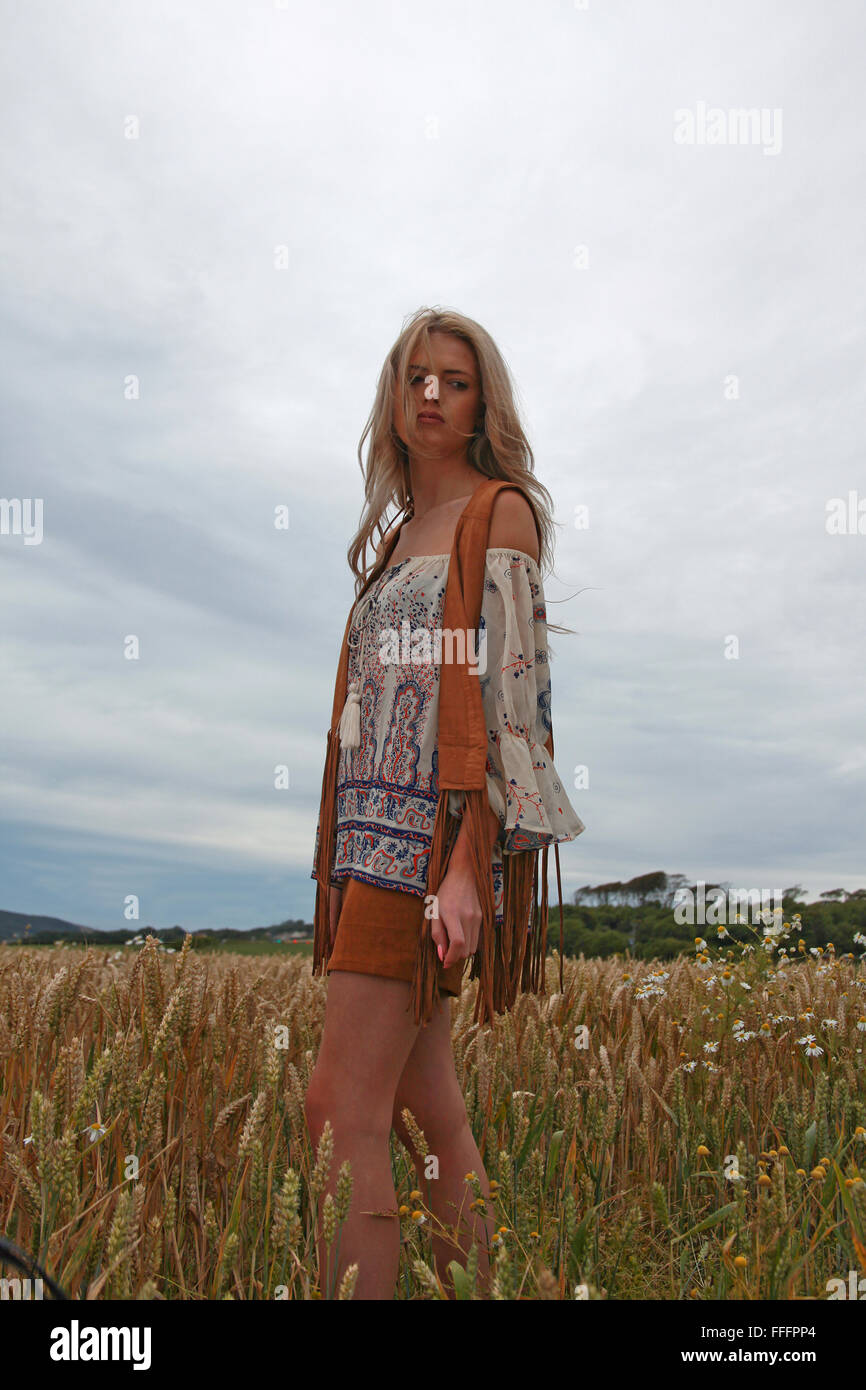 Beautiful girl standing in a meadow with moody sky behind Stock Photo ...
