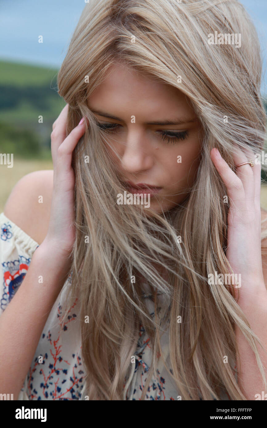 portrait of a beautiful girl with long blonde hair holding her head in ...