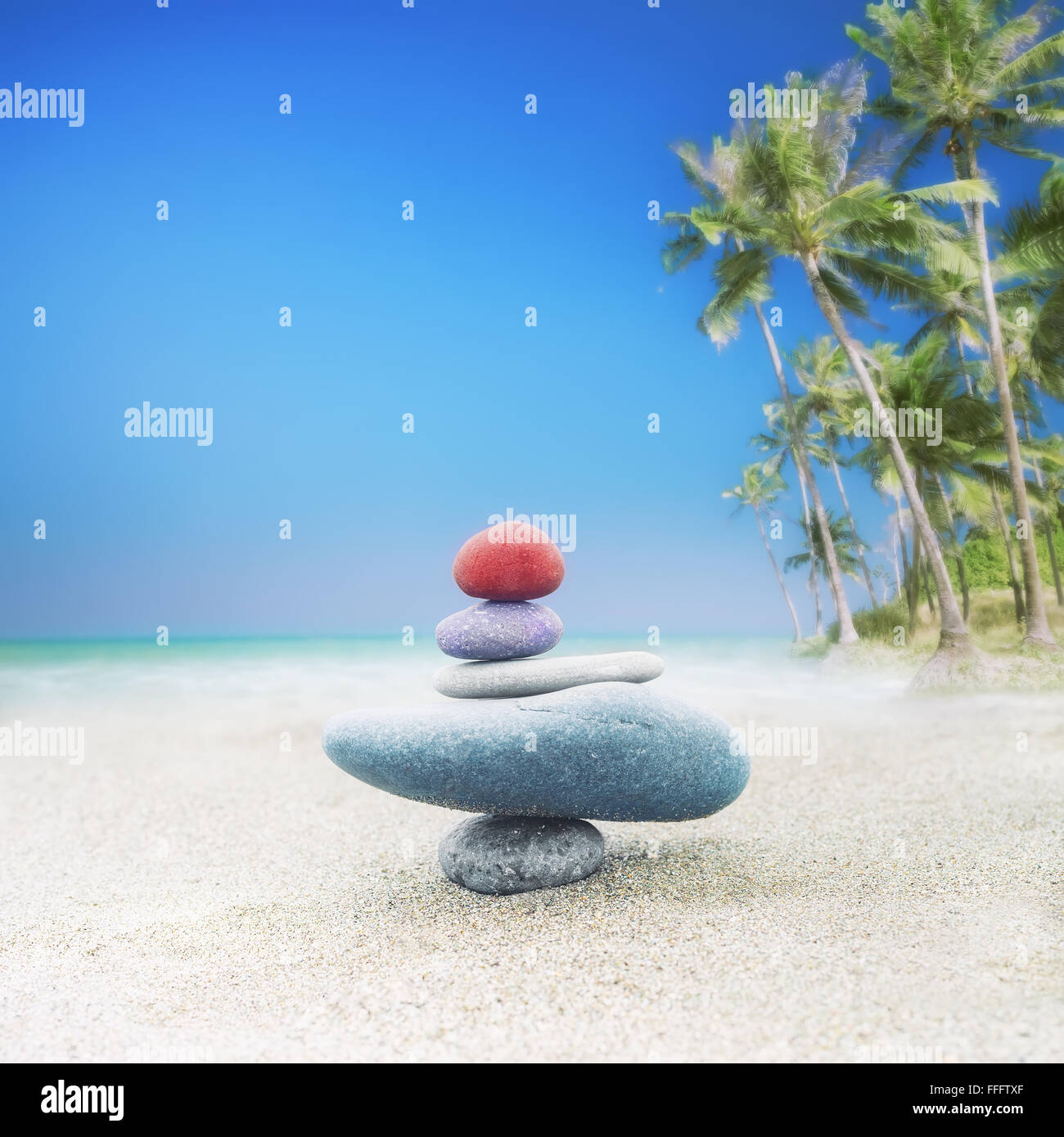 Balancing colorful zen stones pyramid on sandy beach under blue sky. Beautiful nature, travel and spiritual consept Stock Photo