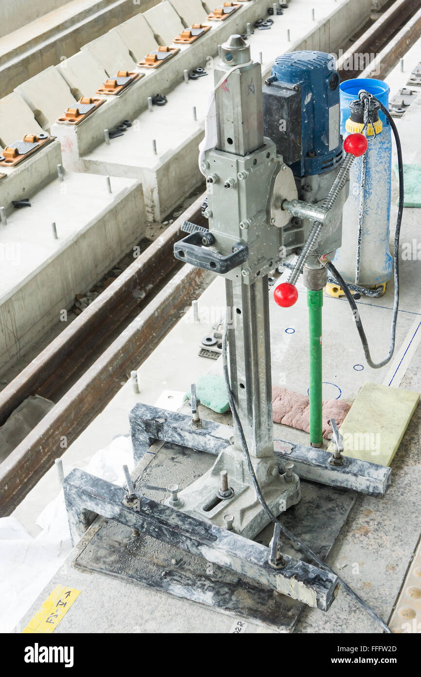 Worker drilling holes in concrete floor at construction site Stock