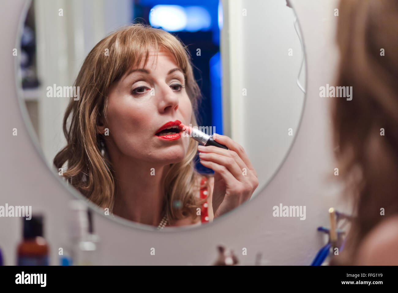 Mature woman applying lipstick. Stock Photo