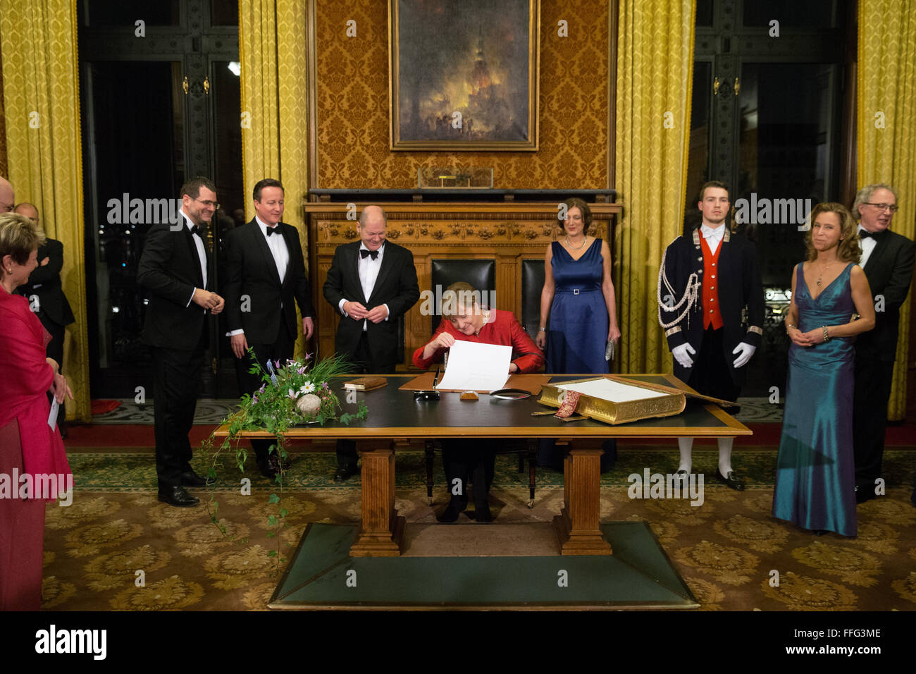 Hamburg, Germany. 12th Feb, 2016. German Chancellor Angela Merkel (C) writes an entry in the city guest book next to British Prime Minister David Cameron (2.f.L), Mayor of Hamburg Olaf Scholz (3.f.L) and his wife Britta Ernst (4.f.R) ahead of the annual 'Matthiae Mahl' banquet in city hall in Hamburg, Germany, 12 February 2016. Merkel and Cameron are this year's guests of honors and the world's oldest banquet, which has been taking place in Hamburg since 1356. Photo: Christian Charisius/dpa/Alamy Live News Stock Photo